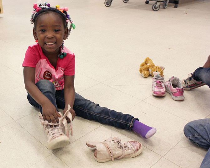 Young girl smiling while she tries on her new shoes