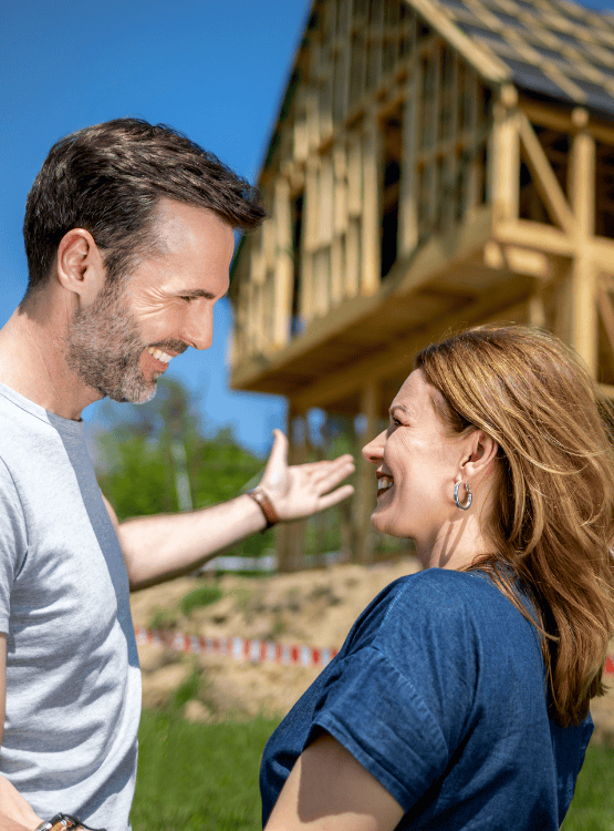 Couple discussing new home construction outside of framed home.