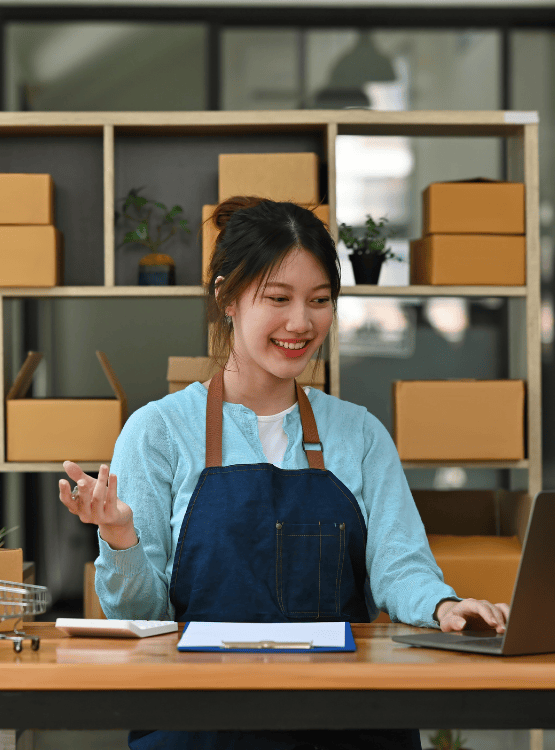 Woman businessowner working on her computer in shop/warehouse. 