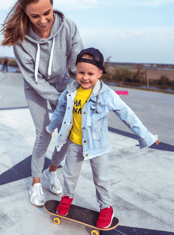 Mother and son skateboarding at skate park. 