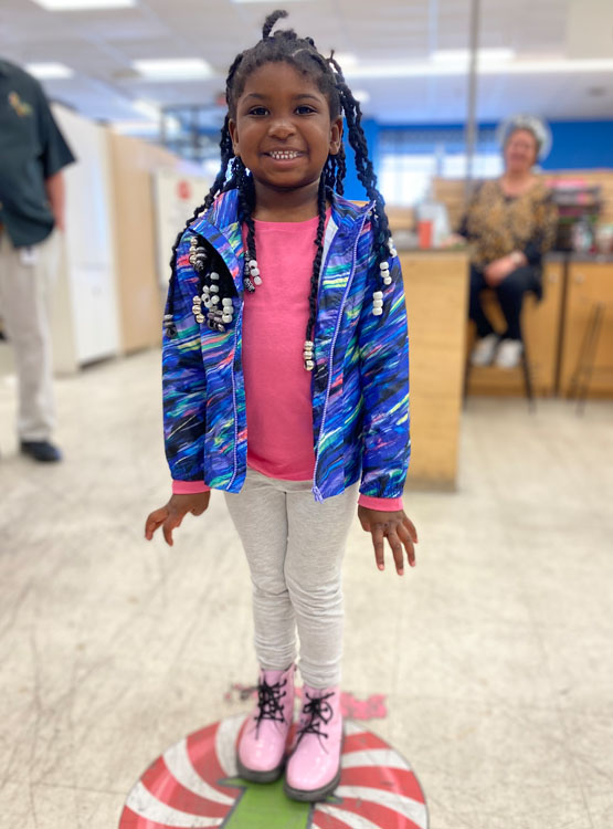 young girl smiling showing off her new pink boots