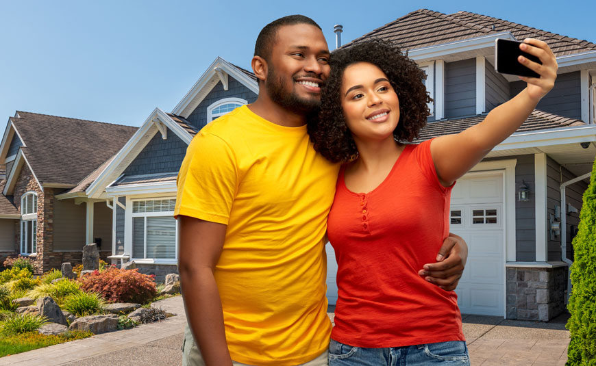 Smiling young couple taking a selfie in front of their new home. 