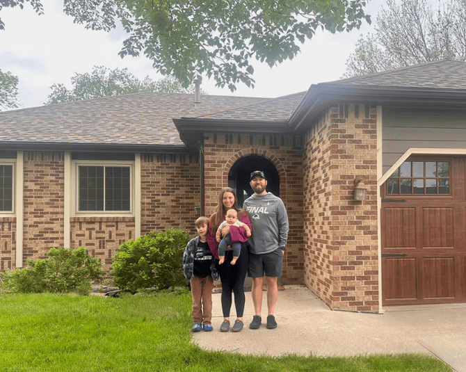 Family posing in front of their new home