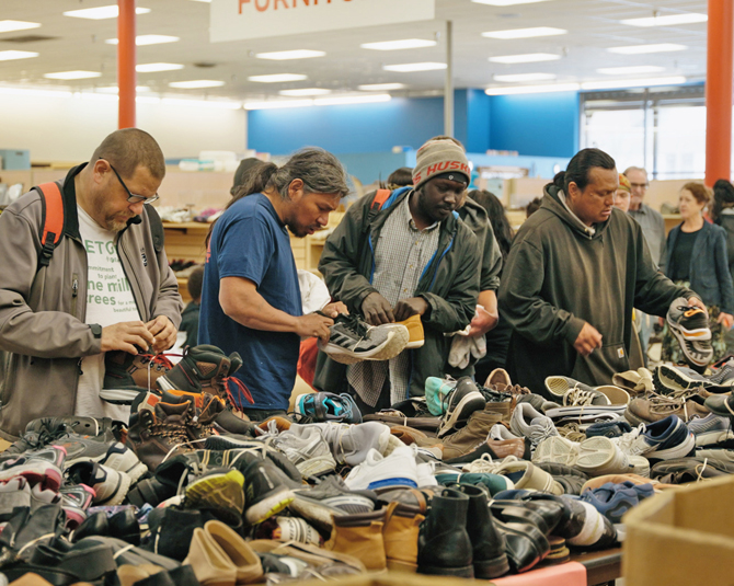 Men sorting through shoes on a table