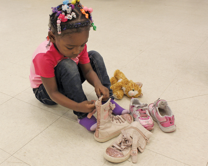 Young girl and her stuffed cat trying on a new pair of shoes