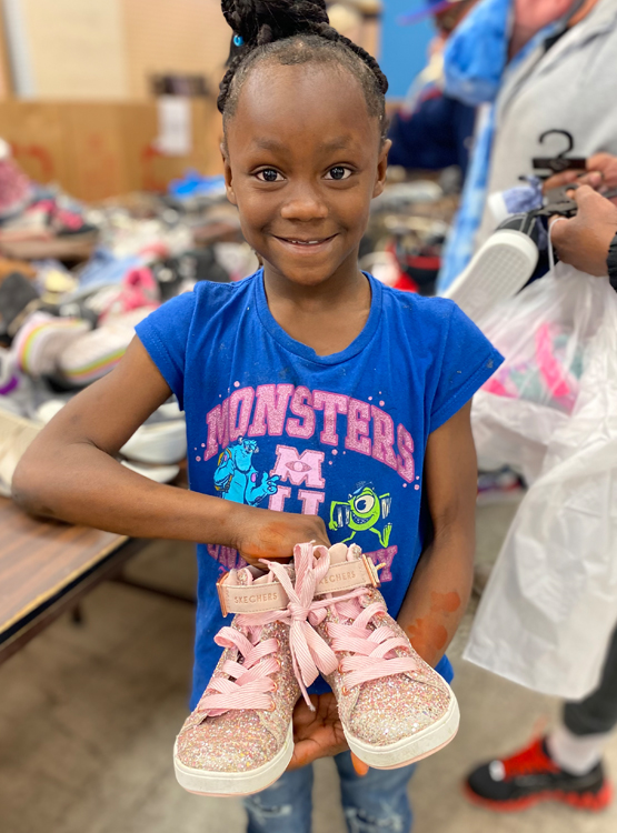 Young girl holding her new shoes from the Day Without Shoes