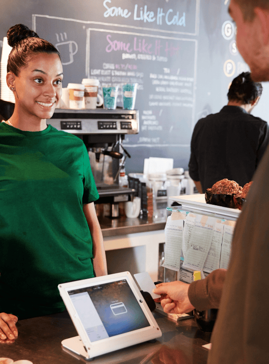 Coffeeshop owner and client using point of sale system to pay for coffee. 