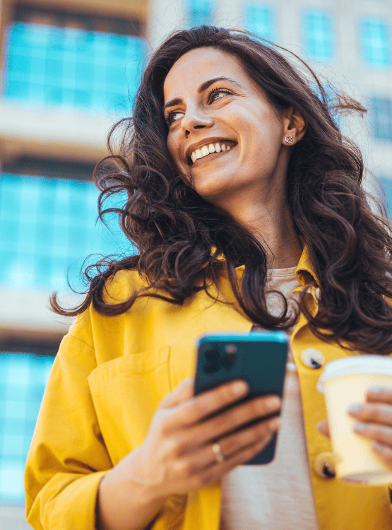 Woman holding her coffee and phone smiling