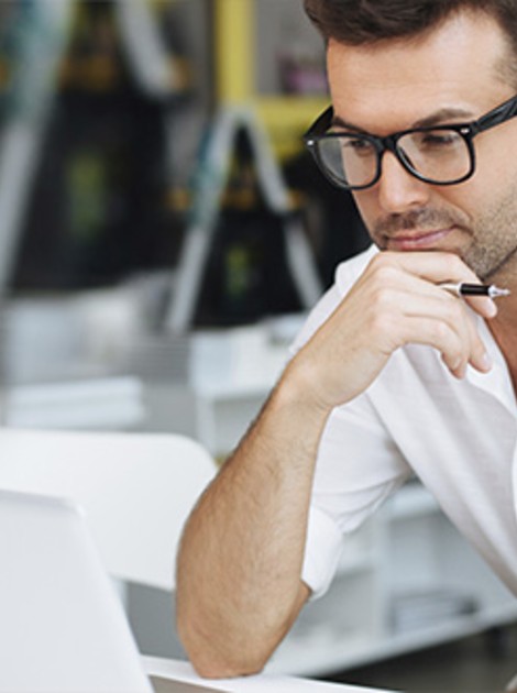 Man holding a pen and looking at his computer